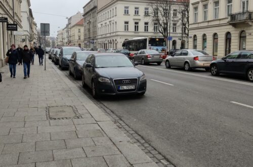 Ulica bez drogi rowerowej, widoczny chodnik i ruch samochodowy, reportażowy kadr.