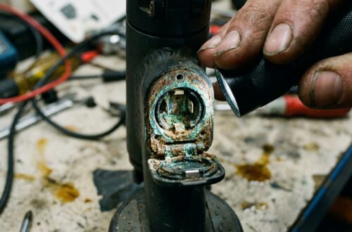 Detal gniazda ładowania hulajnogi z widocznymi oznakami korozji i nalotu.