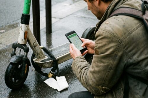 Osoba dokumentuje przypięcie hulajnogi telefonem, widoczny ekran z lokalizacją i zdjęcie miejsca.